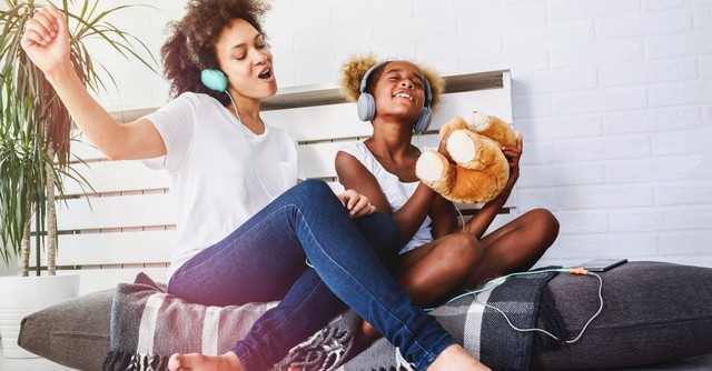 joyful mom and daughter singing praise songs with headphones on