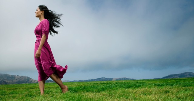 woman standing in flowing dress in field looking into the distance