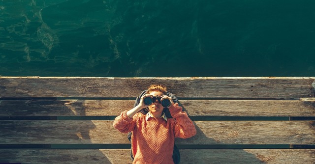 Woman looking up with binoculars