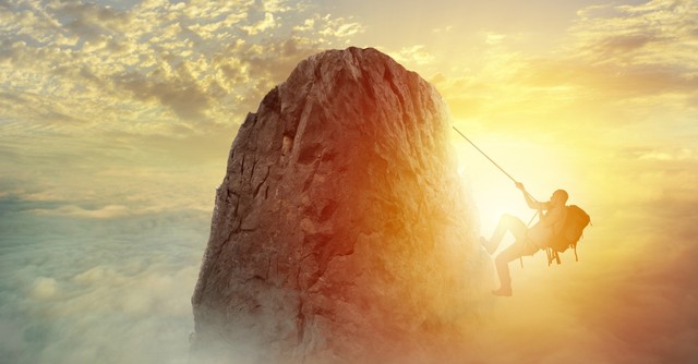 man climbing mountain peak