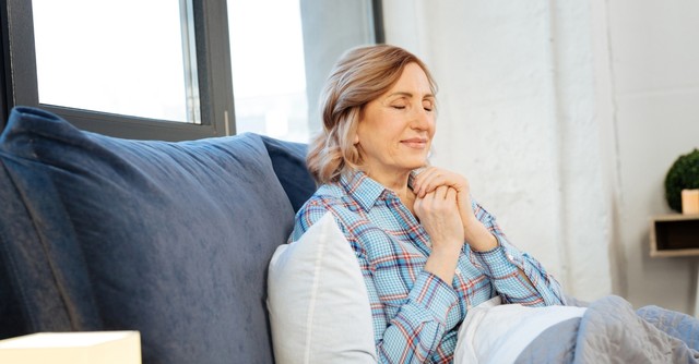 senior woman peacefully praying on her sofa