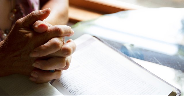 Folded hands over the Bible