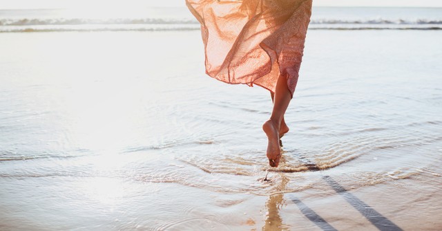 woman running along shore in bare feet