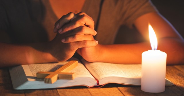 woman praying over a bible with cross and candle, popular bible verses about prayer