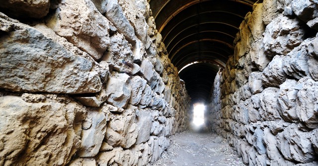stone wall leading to narrow opening with bright light, narrow is the gate
