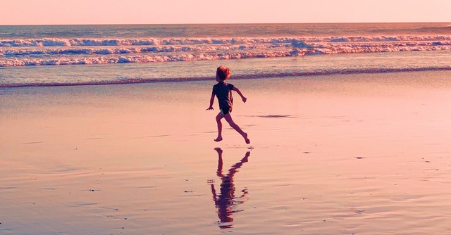 little boy running on a beach at sunset