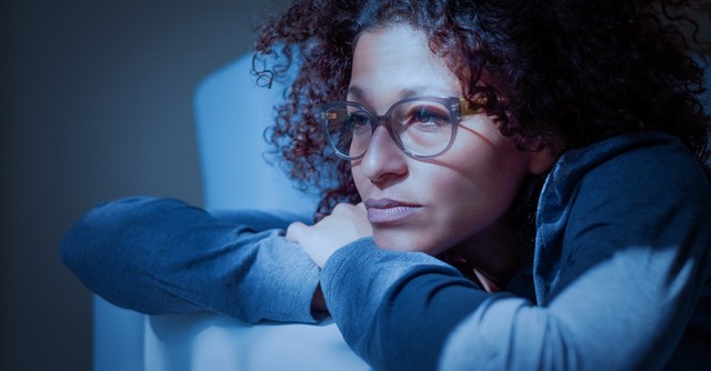 woman looking deeply thoughtful and concerned alone at night