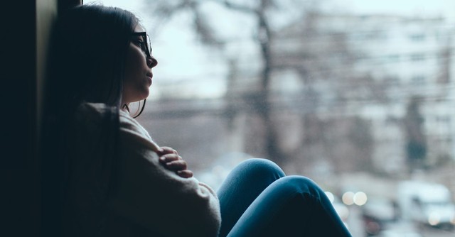 Woman looking sad outside her window