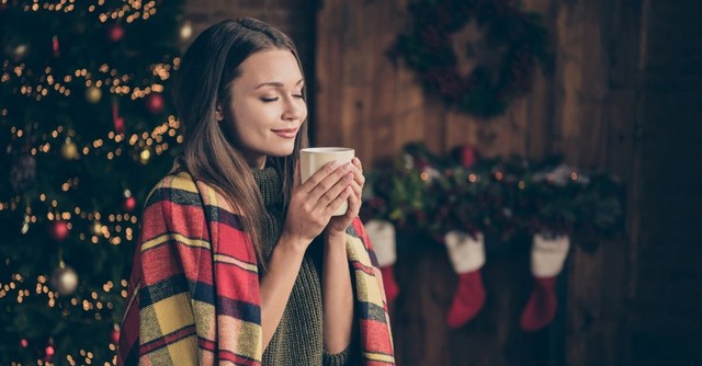 A relaxed woman holding a mug of cocoa at Christmastime