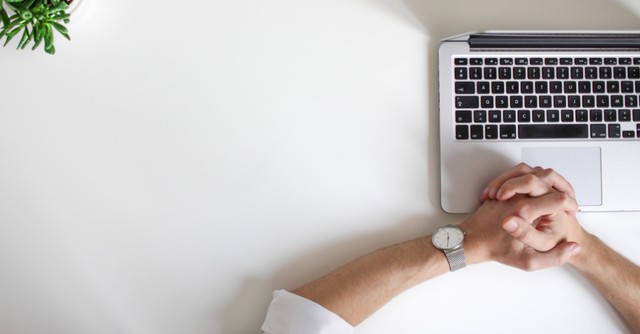 clasped hands by a computer
