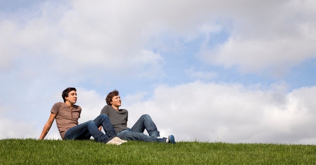 Two young men sitting outside, thinking