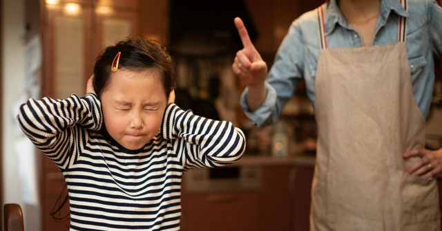 Child with hands over ears, not listening to parent