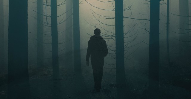 Man walking alone in a dark forest