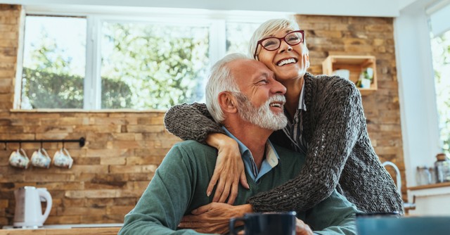 happy senior couple in kitchen hug