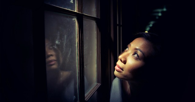 Woman looking out a window, thinking