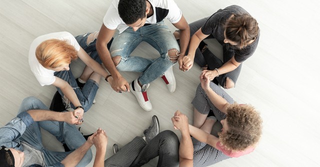 Group of young adults sitting in a circle, praying