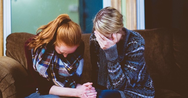 Two sad women, crying and praying together