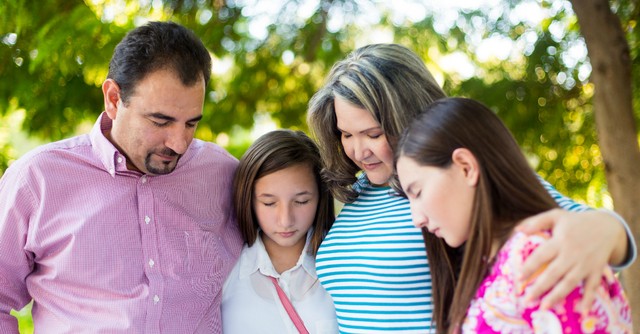 Family praying together outside