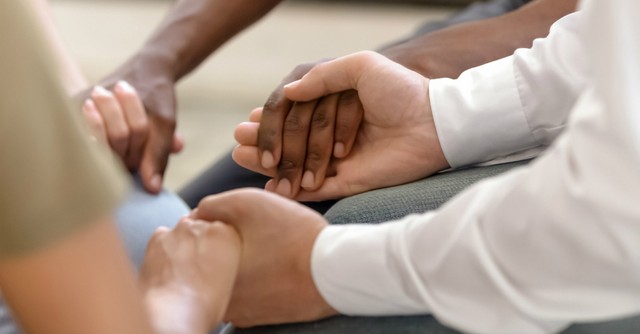 Close-up of a group of people holding hands in prayer