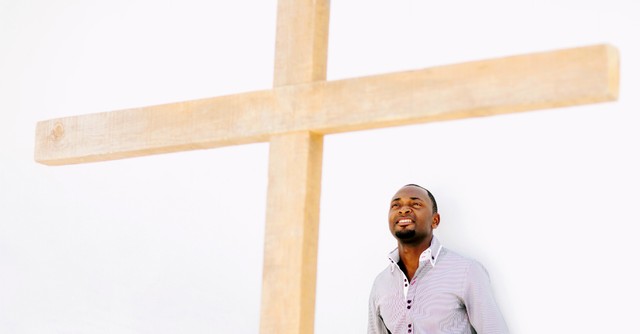 Man smiling, standing in front of cross