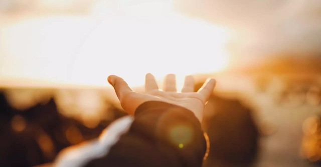 Hand reaching towards the sun