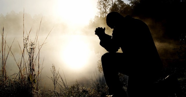 Man kneeling in prayer in the fog