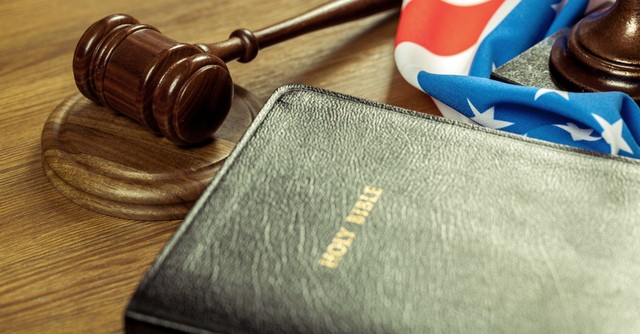 bible on court bench by gavel and flag, crucifixion represents god's justice
