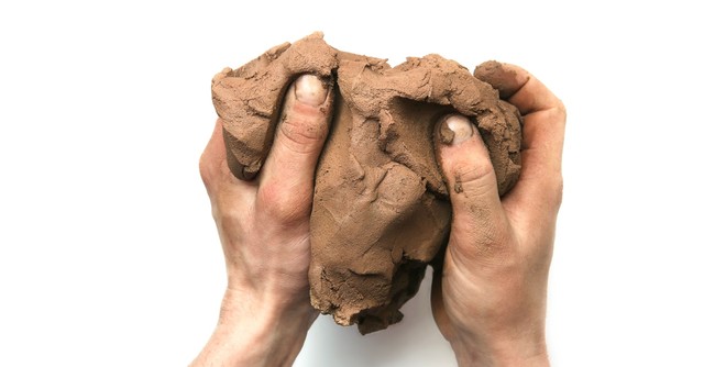 Hands working a large lump of clay