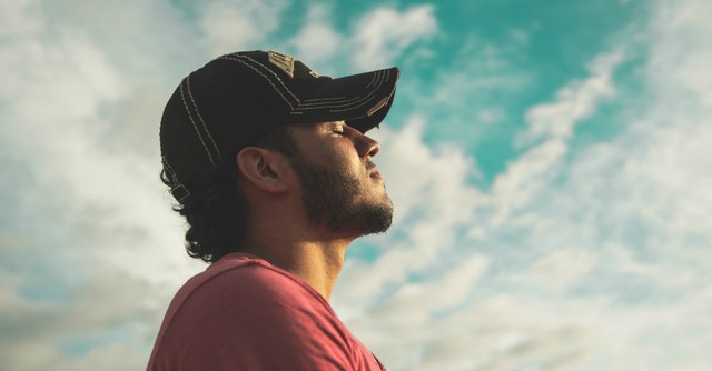Man in a baseball cap tilting his head to the sky