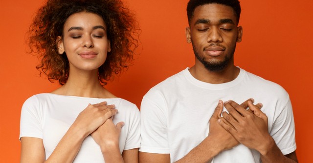 Couple praying with hands over their hearts