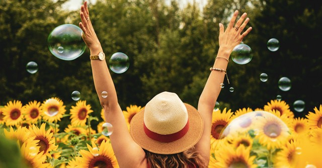 Joyful woman with arms up in a sunflower field