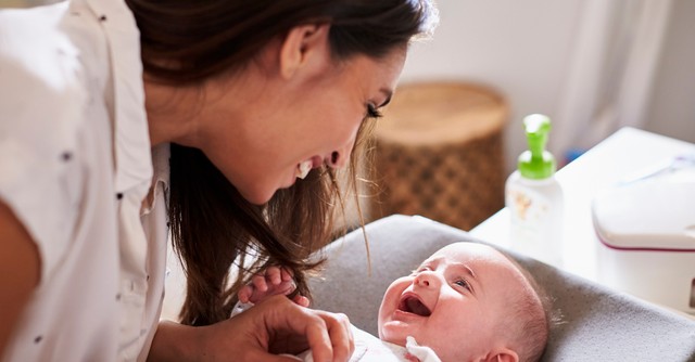 Mom bending over baby, talking and laughing