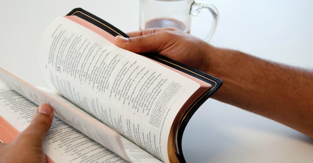 Close up of a man flipping the pages of a Bible