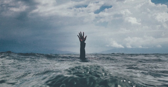 A hand reaching out from deep water
