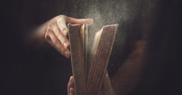 Man opening an old, dusty Bible