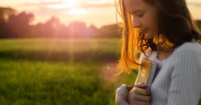 Young woman holding a Bible to her chest