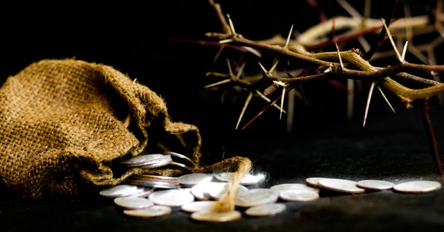 A spilled bag of silver coins with the crown of thorns in the background