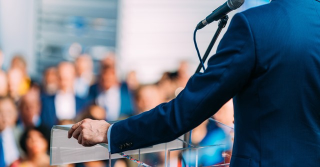 a man at a podium speaking into a microphone