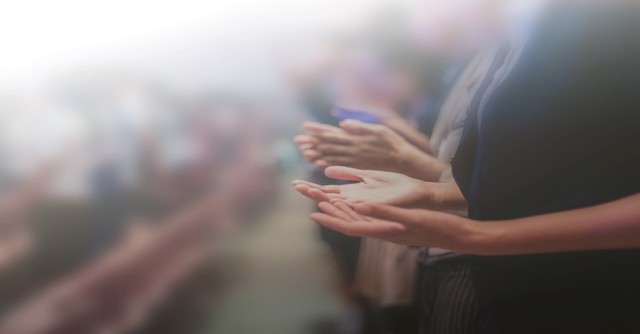 A group of people with hands raised in prayer and worship