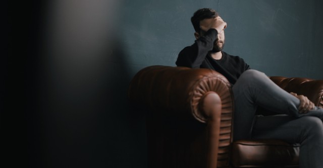 Sad man sitting on a couch in the dark