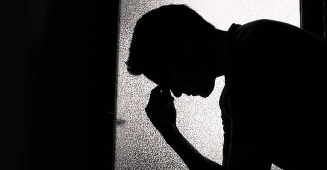 silhouette of man holding his head, sad