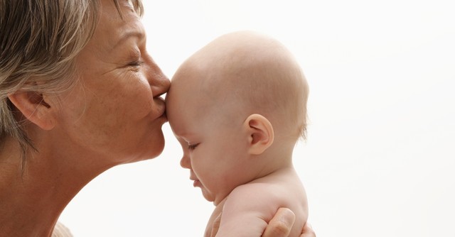 Grandmother kissing a baby on the forehead