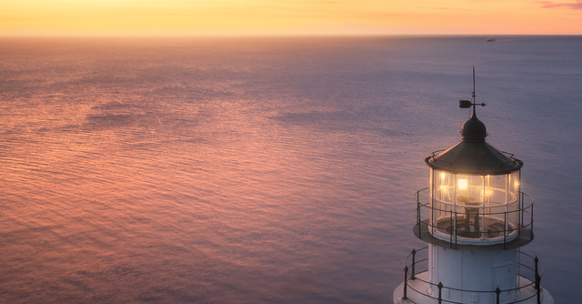 Lighthouse at sunrise, a boat in the distance