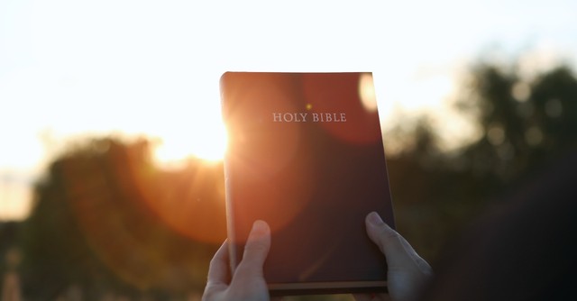 Bible held up in the sunset