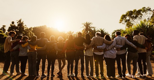 Group of people standing outside in a line with their arms around each other