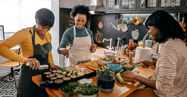 Three women laughing and cooking together