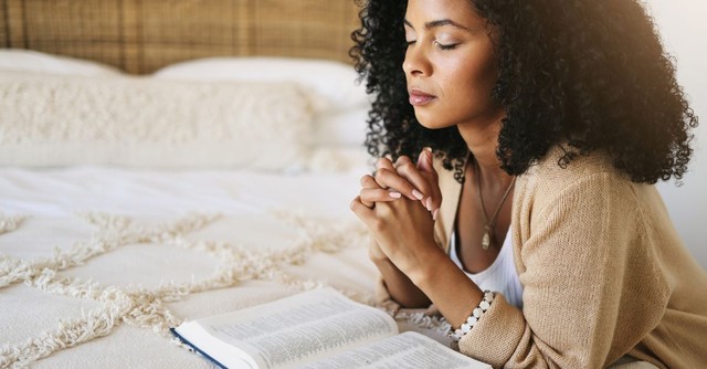 Woman praying, with Bible open;