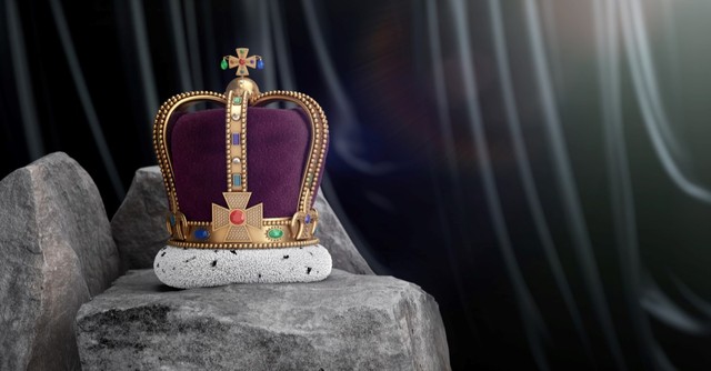 An elaborate purple and gold crown sitting on a rock