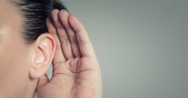Woman holding her hand up to her ear to listen better