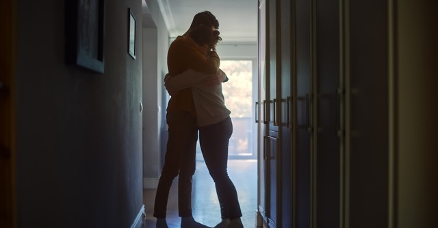 Married couple hugging in a dark hallway
